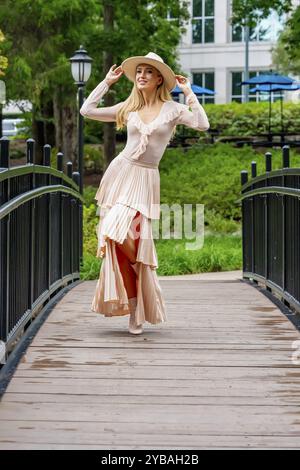 Uno splendido modello mostra la moda autunnale tra la bellezza della natura, trasuda eleganza e fascino in una pittoresca passeggiata nel parco Foto Stock