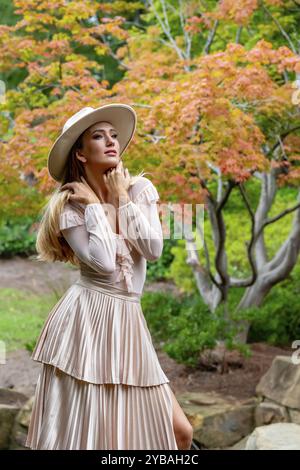 Uno splendido modello mostra la moda autunnale tra la bellezza della natura, trasuda eleganza e fascino in una pittoresca passeggiata nel parco Foto Stock