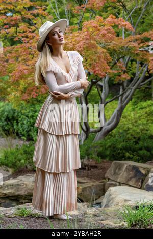 Uno splendido modello mostra la moda autunnale tra la bellezza della natura, trasuda eleganza e fascino in una pittoresca passeggiata nel parco Foto Stock