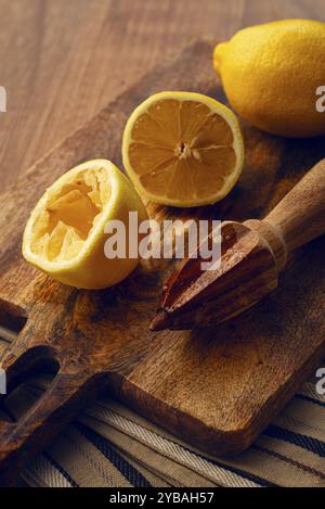 Limoni e spremiagrumi manuali in legno, su un tagliere, primo piano, nessuno Foto Stock