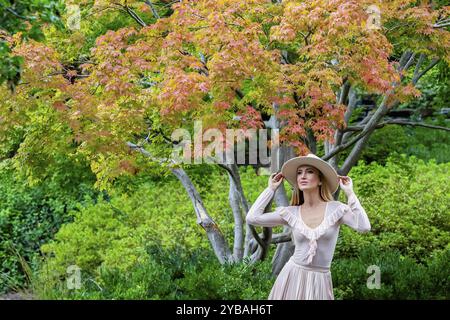 Uno splendido modello mostra la moda autunnale tra la bellezza della natura, trasuda eleganza e fascino in una pittoresca passeggiata nel parco Foto Stock