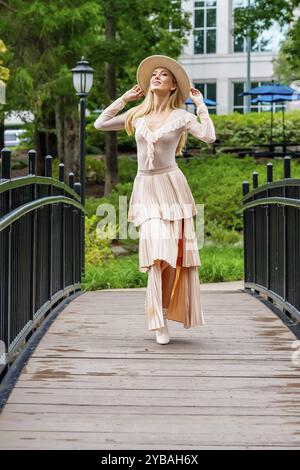 Uno splendido modello mostra la moda autunnale tra la bellezza della natura, trasuda eleganza e fascino in una pittoresca passeggiata nel parco Foto Stock