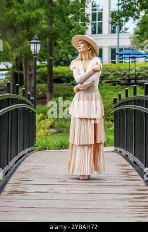 Uno splendido modello mostra la moda autunnale tra la bellezza della natura, trasuda eleganza e fascino in una pittoresca passeggiata nel parco Foto Stock