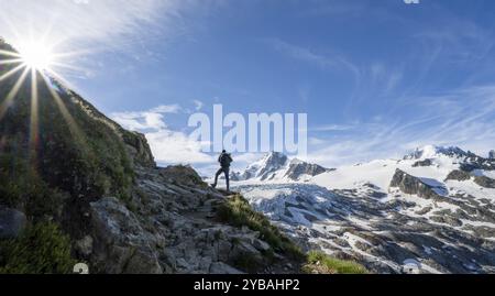 Alpinista di fronte al paesaggio di alta montagna alpina con stella del sole, cima dell'Aiguille de Chardonnet e del Glacier du Tour, ghiacciaio e cime montuose Foto Stock