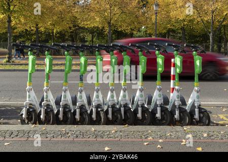 Traffico, mobilità, sfocatura del movimento, auto ed e-scooter allineati dal fornitore Lime in autunno su una strada a Berlino, Germania, Europa Foto Stock