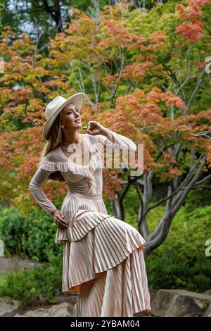 Uno splendido modello mostra la moda autunnale tra la bellezza della natura, trasuda eleganza e fascino in una pittoresca passeggiata nel parco Foto Stock