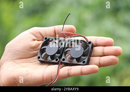 Ventola CPU, nota anche come ventola pc, utilizzata per raffreddare i chip di elaborazione tenuti in mano su uno sfondo di luce naturale Foto Stock