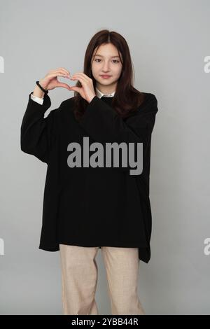 Elegante Teen in versatile felpa con cappuccio nera: Elegante trasuda un'aura premurosa e introspettiva, indossando un'elegante felpa con cappuccio nera perfetta per il branding Foto Stock