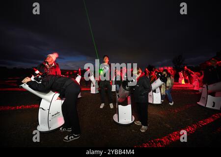 Un gruppo di stelle utilizza i telescopi per dare un'occhiata alla Cometa A3, nota anche come Tsuchinshan-Atlas, e alla luna piena nei cieli sopra la locanda Twice Brewed nel Northumberland International Dark Sky Park, nel nord-est dell'Inghilterra. Data foto: Giovedì 17 ottobre 2024. Foto Stock