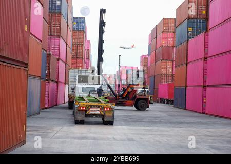 Carrello elevatore a forche per container nel deposito di spedizione con un mucchio di contenitori colorati, spazio di copia, logistica, importazione, esportazione di merci, trasporto in avanti Foto Stock