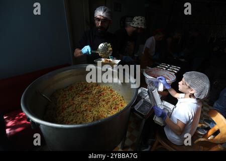 Beirut, Libano. 17 ottobre 2024. La gente lavora in un bar trasformato in una cucina per sfollati a Beirut, Libano, il 17 ottobre 2024. Il numero totale di sfollati in Libano a causa di attacchi aerei israeliani è salito a quasi 1,2 milioni, secondo un rapporto pubblicato mercoledì dall'unità di gestione del rischio di catastrofi presso il Consiglio dei ministri libanese. Crediti: Bilal Jawich/Xinhua/Alamy Live News Foto Stock