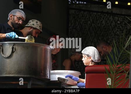 Beirut, Libano. 17 ottobre 2024. La gente lavora in un bar trasformato in una cucina per sfollati a Beirut, Libano, il 17 ottobre 2024. Il numero totale di sfollati in Libano a causa di attacchi aerei israeliani è salito a quasi 1,2 milioni, secondo un rapporto pubblicato mercoledì dall'unità di gestione del rischio di catastrofi presso il Consiglio dei ministri libanese. Crediti: Bilal Jawich/Xinhua/Alamy Live News Foto Stock