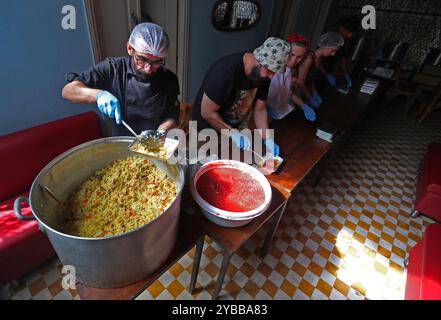 Beirut, Libano. 17 ottobre 2024. La gente lavora in un bar trasformato in una cucina per sfollati a Beirut, Libano, il 17 ottobre 2024. Il numero totale di sfollati in Libano a causa di attacchi aerei israeliani è salito a quasi 1,2 milioni, secondo un rapporto pubblicato mercoledì dall'unità di gestione del rischio di catastrofi presso il Consiglio dei ministri libanese. Crediti: Bilal Jawich/Xinhua/Alamy Live News Foto Stock