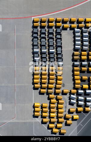 Vista dall'alto dei carrelli per bagagli gialli e neri vuoti sull'asfalto dell'aeroporto Foto Stock