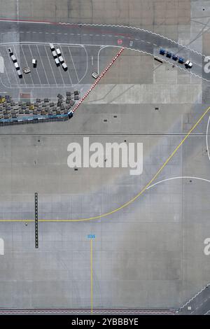 Vista dall'alto dei carrelli portabagagli e dei cartelli stradali sulla soleggiata asfalto dell'aeroporto Foto Stock