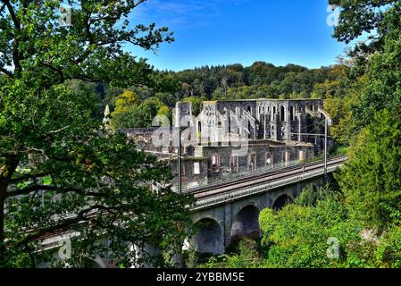 Splendida Abbazia di Villers del XII secolo circondata da foglie autunnali in una giornata di sole vista da dietro un viadotto ferroviario. Villers-la-Ville, Belgio. Foto Stock