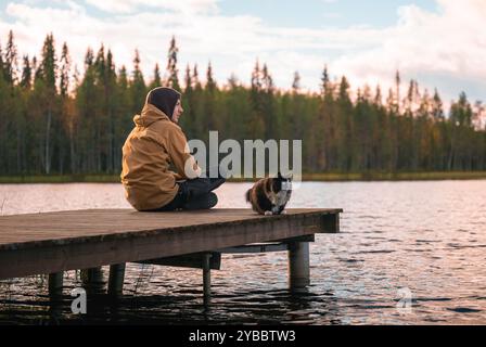 Uomo con gatto seduto su un molo di legno Foto Stock