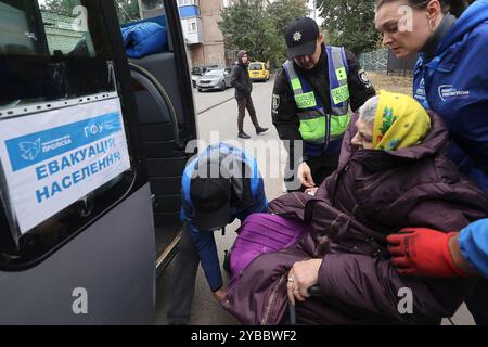 CHARKIV, UCRAINA - 17 OTTOBRE 2024 - Un ufficiale di polizia e volontari aiutano una donna anziana in sedia a rotelle a scendere dall'autobus in un punto di evacuazione durante l'arrivo di persone dalla comunità di Kupiansk, Charkiv, Ucraina nord-orientale. L'evacuazione obbligatoria da quattro comunità nella regione di Charkiv è iniziata a causa delle ostilità. Foto Stock