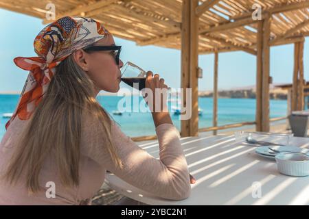 Una donna è seduta a un tavolo con un bicchiere di birra davanti a lei Foto Stock