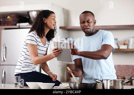 Coppia africana, tablet e cucina in cucina a casa con lezione online, tutorial virtuale e confusa con una cattiva ricetta. Uomo, donna e tecnologia Foto Stock