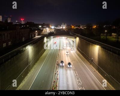 Sentieri leggeri da auto che guidano su un'autostrada, passando sotto un ponte di notte, nel centro di liverpool Foto Stock