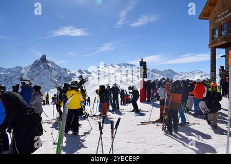 Meribel, Francia - 13 marzo 2024: Cima delle stazioni sciistiche Meribel e Courchevel, tre valli. Sciatori e snowboarder sulla cima del monte Saulire. Foto Stock