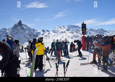 Meribel, Francia - 13 marzo 2024: Cima delle stazioni sciistiche Meribel e Courchevel, tre valli. Sciatori e snowboarder sulla cima del monte Saulire. Foto Stock