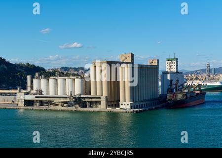 Barcellona, Spagna - 28 settembre 2024: Veduta aerea del porto industriale di Barcellona con silos di grano e una nave da carico per il carico e lo scarico. Foto Stock