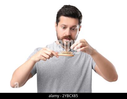 Uomo triste che prende i capelli persi dalla spazzola su sfondo bianco. Problema di alopecia Foto Stock