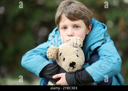 Concetto di autismo. Bambino solitario con orsacchiotto all'aperto Foto Stock