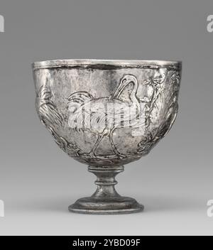 Coppa con gru, 25 a.C.-D.A. 50. Ulteriori informazioni: Quattro gru mostrate nel loro ambiente paludoso naturale decorano questa coppa d'argento romana. Gli uccelli si nutrono e cacciano tra la vegetazione, cercando soprattutto serpenti di varie dimensioni. Le gru, le cui coppie fiancheggiano una pianta centrale, sono raffigurate in una varietà di pose: Una si batte contro un serpente intrecciato con le sue gambe; una seconda preserva le piume della sua schiena; una terza cattura un serpente nascosto sotto una pianta fiorita e la quarta preserva le sue piume alari. La scena naturale su questa coppa potrebbe rappresentare un paesaggio accanto al fiume Nilo. Tali immagini sono state create in Un Foto Stock