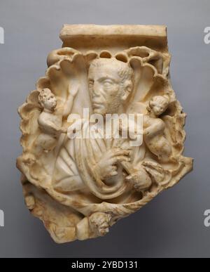 Roman Sarcophagus Fragment, circa d.C. 250-275. Ulteriori informazioni: Frammento di sarcofago conserva la parte centrale con conchiglia contenente un busto ritratto di un uomo. Il guscio è tenuto da due mani su entrambi i lati (forse centauri marini). Una piccola ala è conservata accanto alla mano superiore a destra (evidentemente un eros volante). Sotto il guscio c'è una mano di una piccola figura girata a destra (Scilla con timone). All'interno del guscio, il busto di un uomo che indossa una tunica e un indumento esterno con la punta appesa all'avambraccio sinistro. Sta tenendo un rotolo con la mano sinistra. Su entrambi i lati, all'interno della shell, gli erotes sono ap Foto Stock