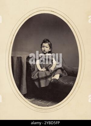 George Fauntleroy Davidson, circa 1865 anni. Un ritratto in studio di un giovane ragazzo su un piccolo divano. Sta indossando un vestito di colore scuro. Foto Stock