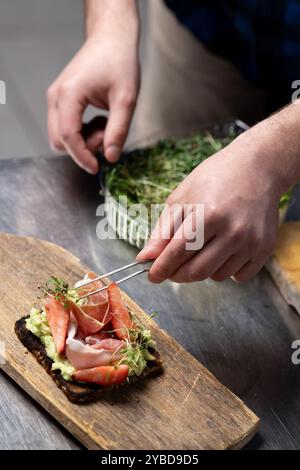 Assemblaggio di panini gourmet a vista con ingredienti freschi in cucina Foto Stock