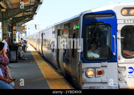 Woodside, New York, Stati Uniti d'America - 20 agosto 2024: Treno ferroviario di Long Island in arrivo a Woodside con persone in attesa di recarsi a New York. Foto Stock