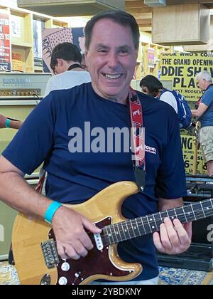 Cleveland, Ohio, USA - 4 agosto 2023: Un musicista sorridente si impegna con una chitarra nella Rock and Roll Hall of Fame. Foto Stock