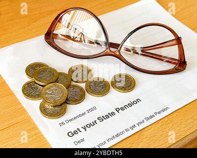 Lettera ufficiale che dice a una persona in età pensionabile statale nel Regno Unito che può ottenere la pensione, con monete da una sterlina e un paio di occhiali da lettura. Foto Stock