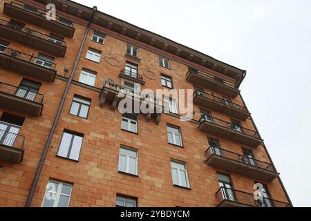 Mentre guardo verso l'alto una imponente e grande struttura in mattoni, ammiro i suoi numerosi balconi che abbelliscono ogni livello dell'edificio Foto Stock