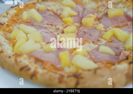 Primo piano di una classica pizza hawaiana condita con prosciutto e succosi pezzi di ananas Foto Stock