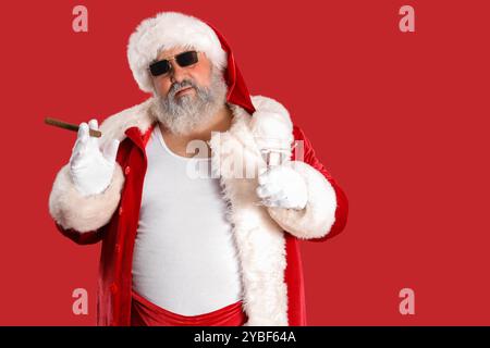 Babbo Natale cattivo con sigaro e cocktail su sfondo rosso Foto Stock