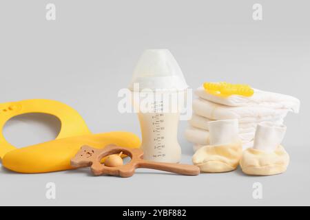 Biberon con latte artificiale e diversi accessori su sfondo chiaro Foto Stock