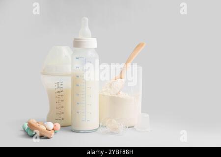 Biberon con latte artificiale, massaggiagengive e succhietto su sfondo chiaro Foto Stock