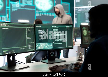 Team di hacker governativi che proteggono i sistemi informatici dalle minacce informatiche, lavorando insieme nella sala di controllo dell'agenzia. Enfatizzare la crittografia, la sicurezza online e lo spionaggio contro gli attacchi informatici. Foto Stock