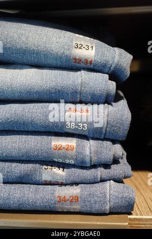 Un'esposizione ben impilata di jeans piegati con etichette delle taglie in un ambiente di vendita al dettaglio Foto Stock