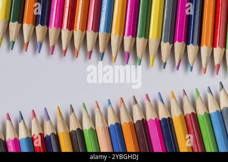 Composizione astratta di un insieme di legno matite di colore contro uno sfondo bianco Foto Stock