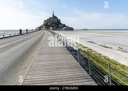 Mont Saint Michel, Francia, 25 luglio 2018: Veduta di Mont Saint-Michel contro il cielo. Ciclisti sul lungomare, Europa Foto Stock