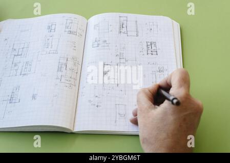 Architect disegna schizzi su notebook su sfondo verde Foto Stock