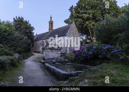 Antica cappella romanica in Locronan durante la notte. La cattedrale di Notre Dame de Bonne Nouvelle et sa Fontaine Foto Stock