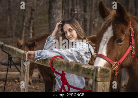 Una bella cowgirl brunetta posa con il suo cavallo prima di un giro in campagna Foto Stock