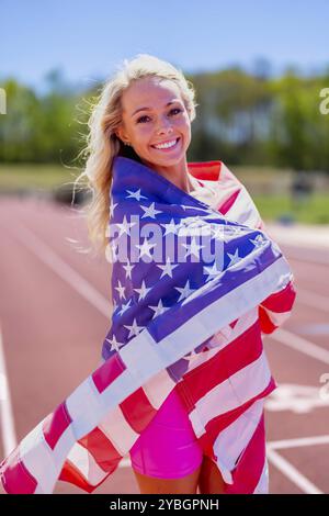 L'orgogliosa atleta americana sventola la bandiera degli Stati Uniti, onorando il suo paese dopo un trionfale incontro su pista locale, incarnando patriottismo e rispetto Foto Stock